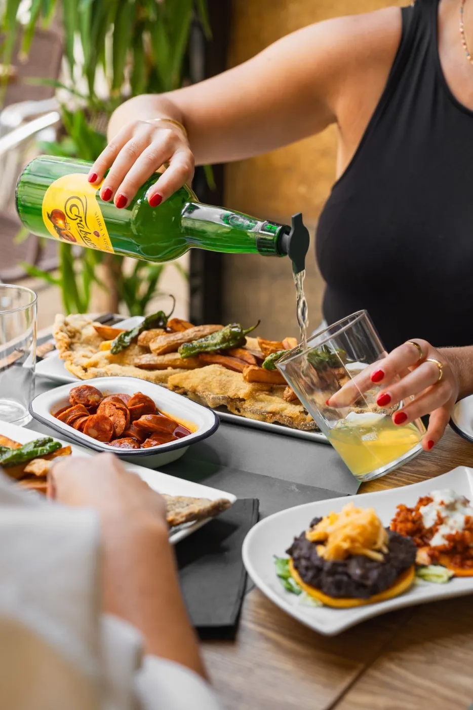 Sirviendo sidra natural asturiana junto a tortos de maíz y pimientos fritos en La Kchoperia