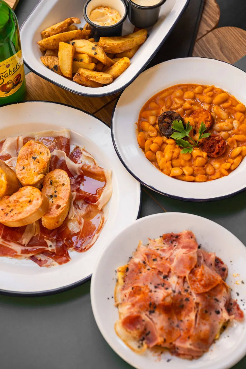 Mesa compartida con fabada asturiana, jamón y embutidos en La Kchoperia, Reus