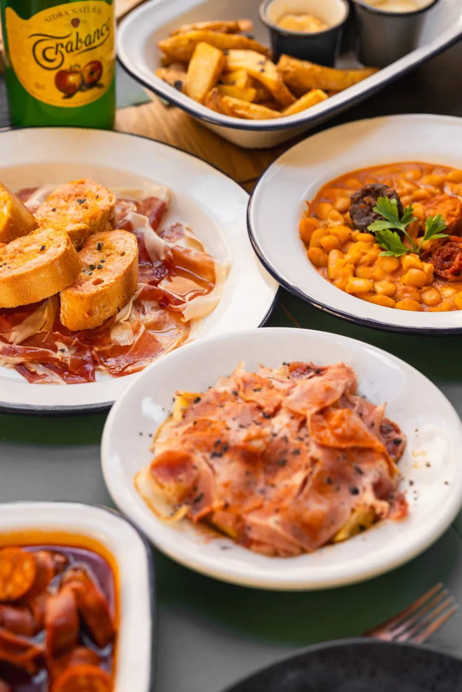 Surtido de platos asturianos para compartir: fabada, jamón y embutidos en La Kchoperia